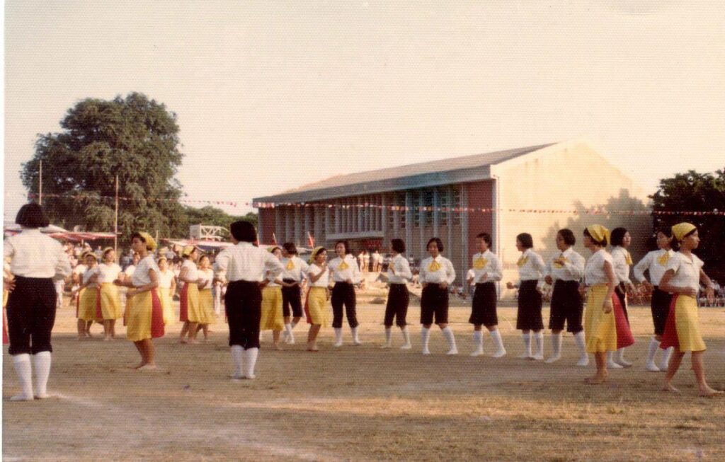 1976 年之酸果樹與舊體育館。畫面中學生正在練習運動會的舞蹈表演